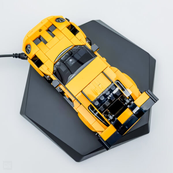 Batterie de voiture jaune en LEGO sur une plateforme noire, modèle détaillé, parfait pour les amateurs de construction et de voitures.