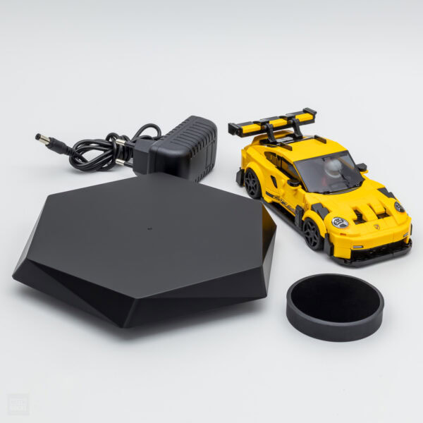Alt : Set de chargeur pour voiture télécommandée LEGO, incluant un adaptateur, une base de chargement et une voiture LEGO jaune avec aileron.