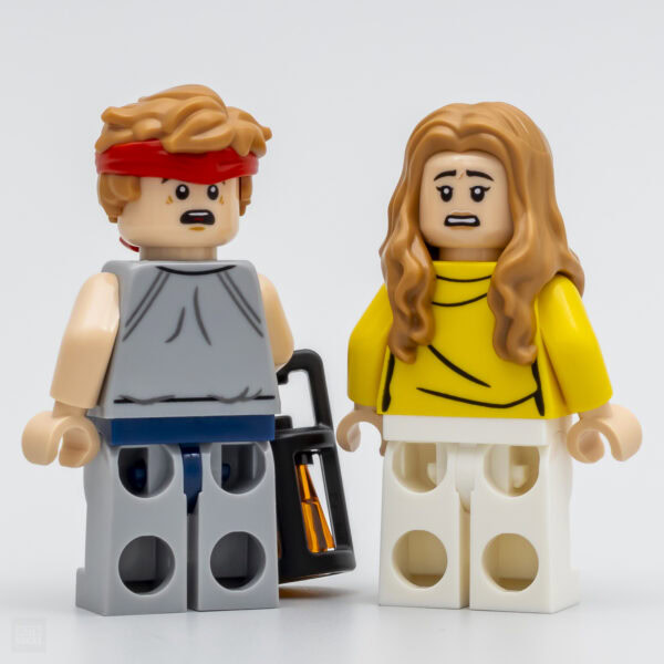 Légende: Figurines LEGO inspirées de la culture pop, représentant un homme en tenue décontractée avec une tête bandée rouge et une femme en chemisier jaune avec cheveux longs bouclés.