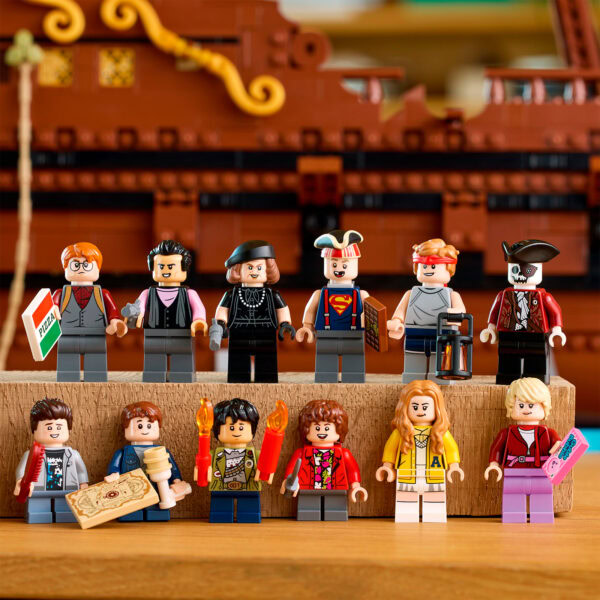 LEGO minifigures collection avec personnages de pirates, super héros, pirates, explorateurs, et héros légendaires, posés sur une surface en bois avec un bateau en arrière-plan.