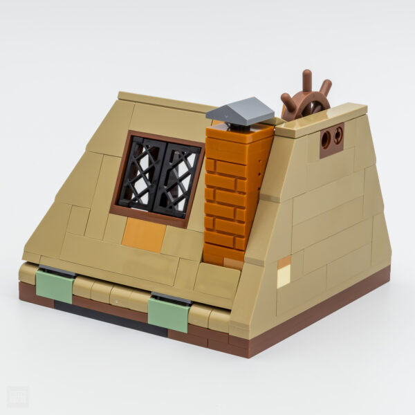 Vieux chalet en briques LEGO avec cheminée et fenêtre en grillage, construit avec des briques de diverses couleurs pour un rendu réaliste et détaillé.