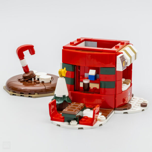 Miniature maison en briques Lego autour de Noël, thème de fête avec décorations, détails festifs et couleurs vives pour une ambiance chaleureuse et conviviale.